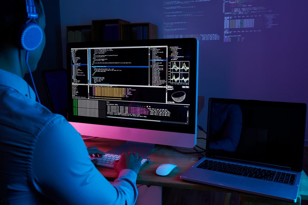 Programador en auriculares revisando su código en la pantalla de la computadora